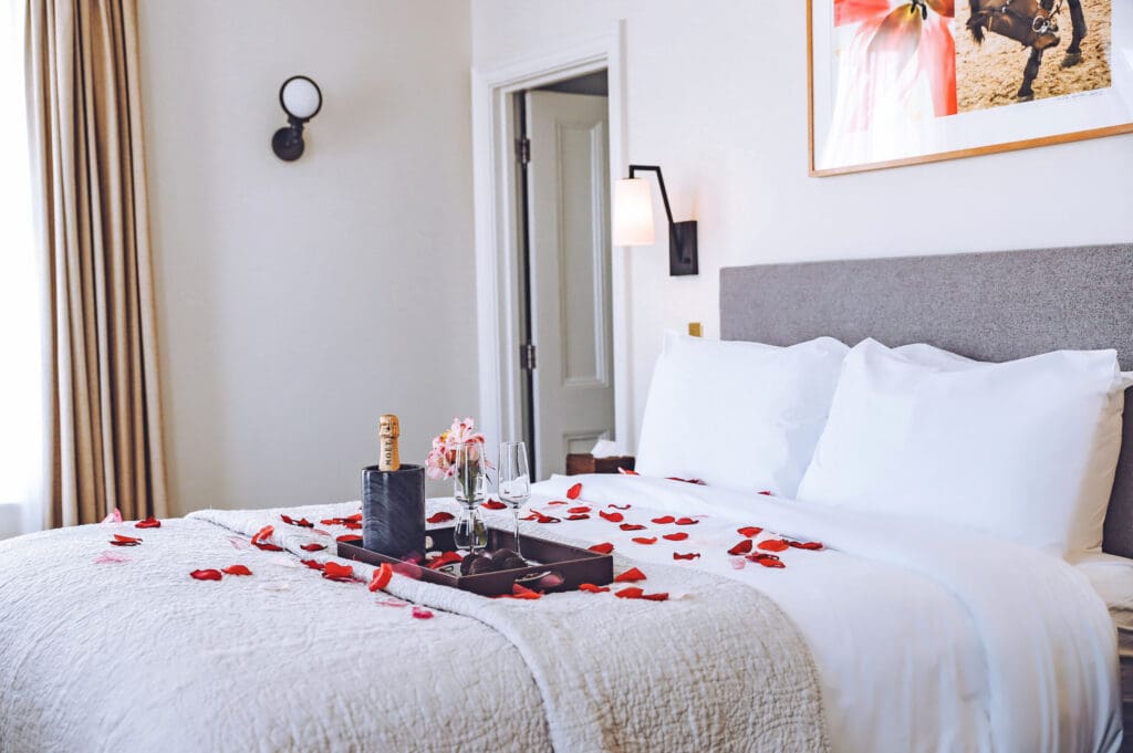 Image of rose petals and champagne on bed at La Posada Milford hotel