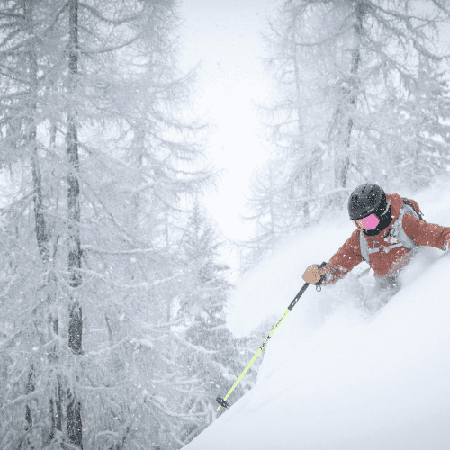 Image of skier in waist deep snow down hill