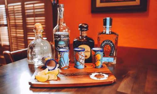 Display of various tequila bottles and tasting board at La Posada Milford
